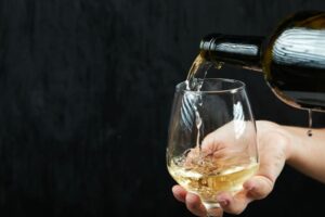 verter-vino-blanco-copa-vino-sobre-superficie-oscura